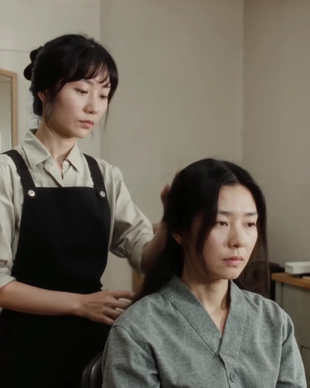 美容室で、スタイリストが鏡ごしにお客様と髪の長さを確認している