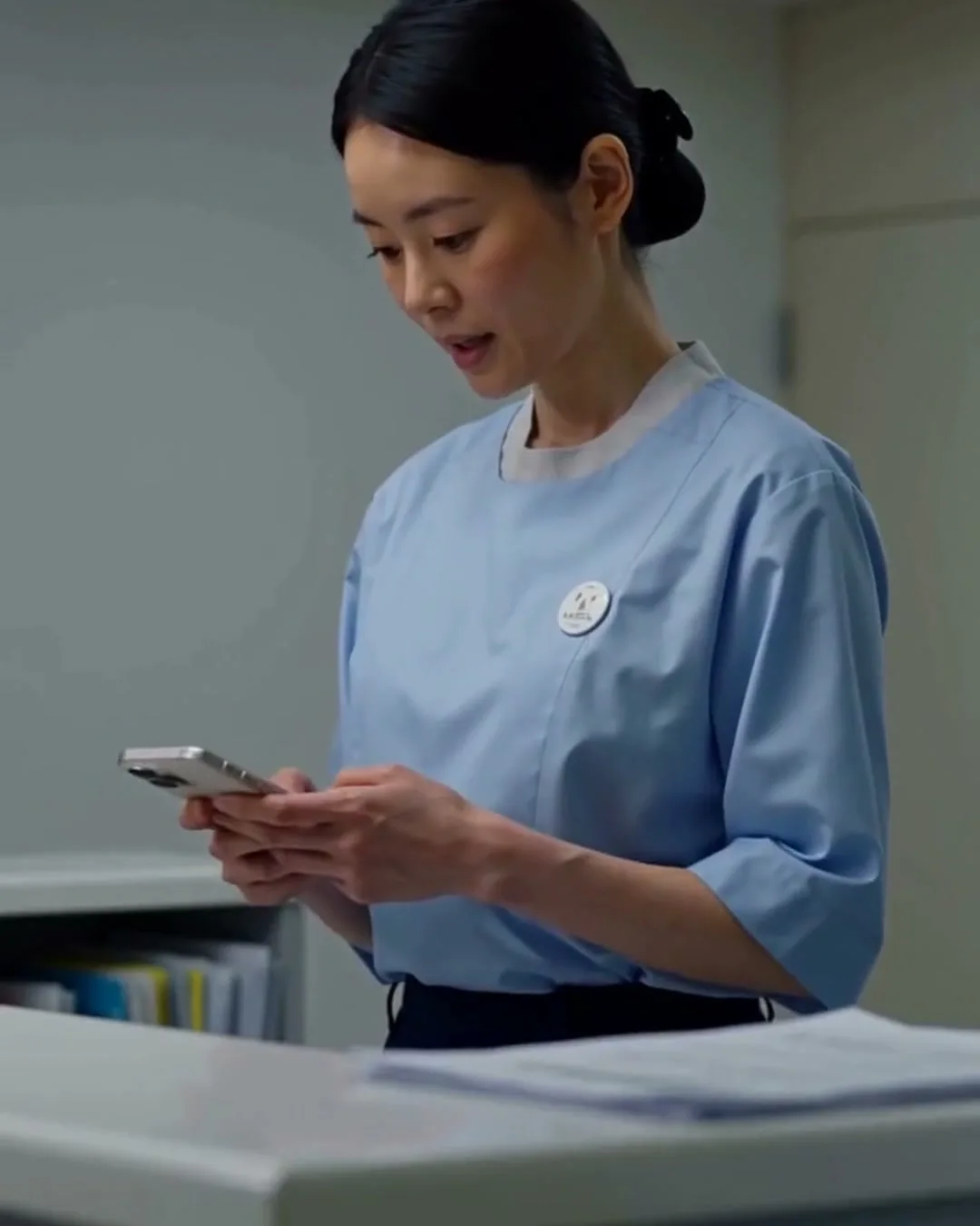 受付スタッフがカウンターでスマートフォンを持ち、患者の訳文を確認している