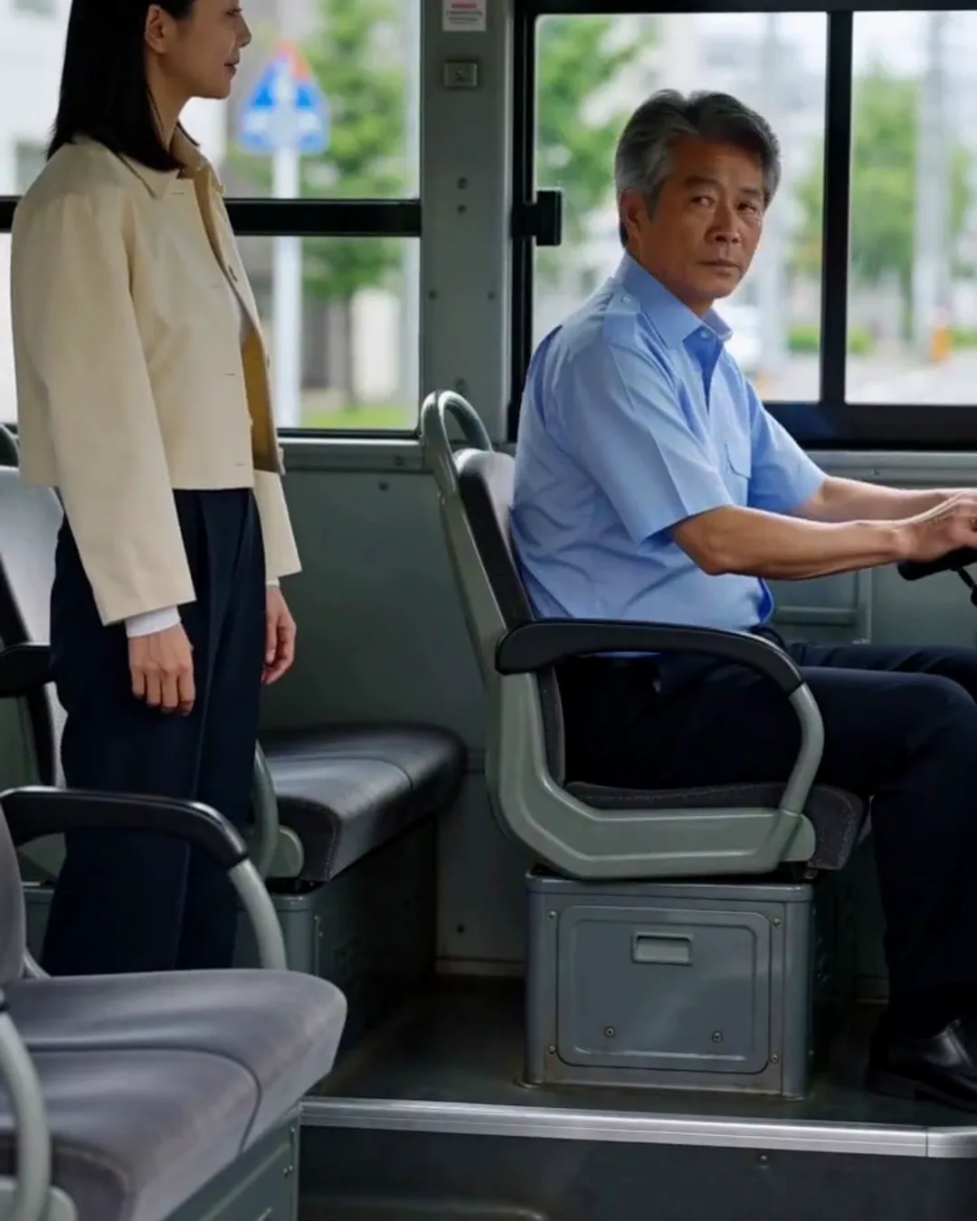 停車中の路線バスの運転席の横で、運転手が振り返って外国人の女性客と話している