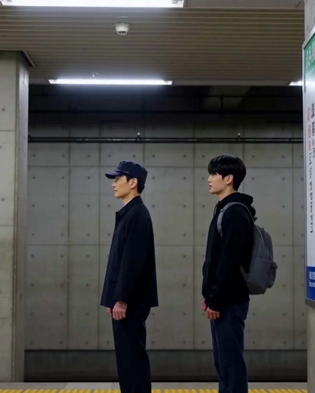 地下鉄のホームで、駅員の男性と外国人の男性客が向かい合って話している