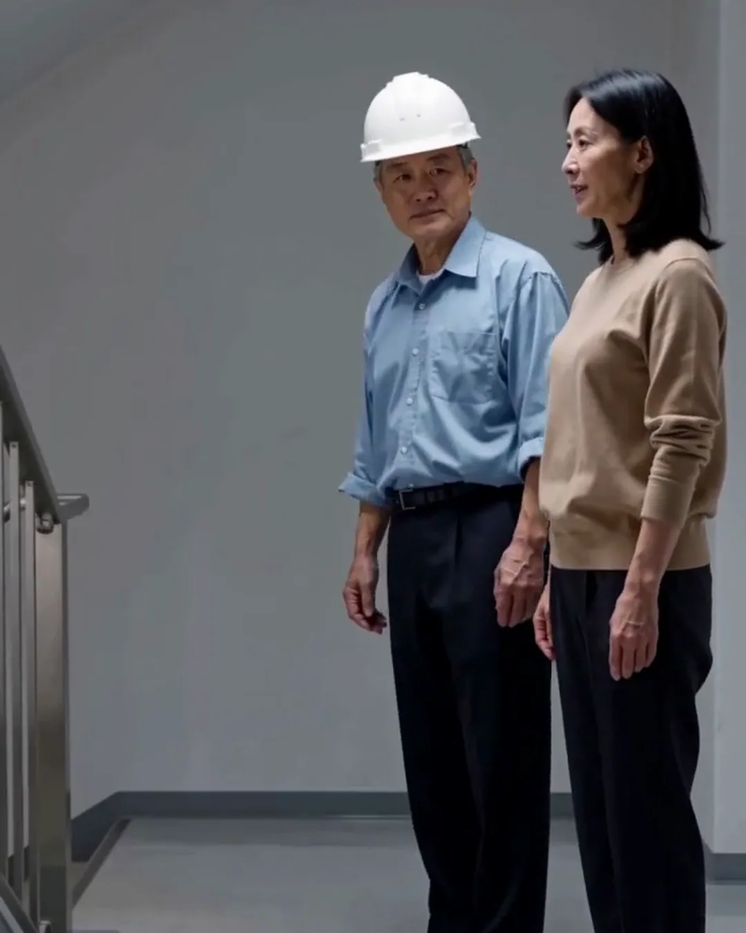 マンションの廊下で、管理人と外国人の女性住民が避難経路を確かめている