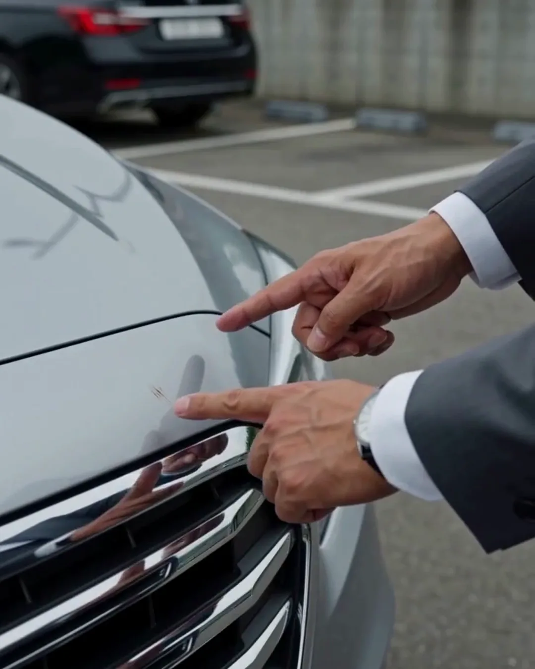 車のバンパーの傷を指さしている手元
