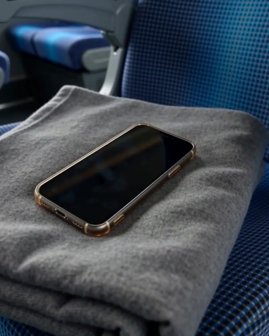 高速バスの座席に置かれた、グレーのブランケットとスマートフォン