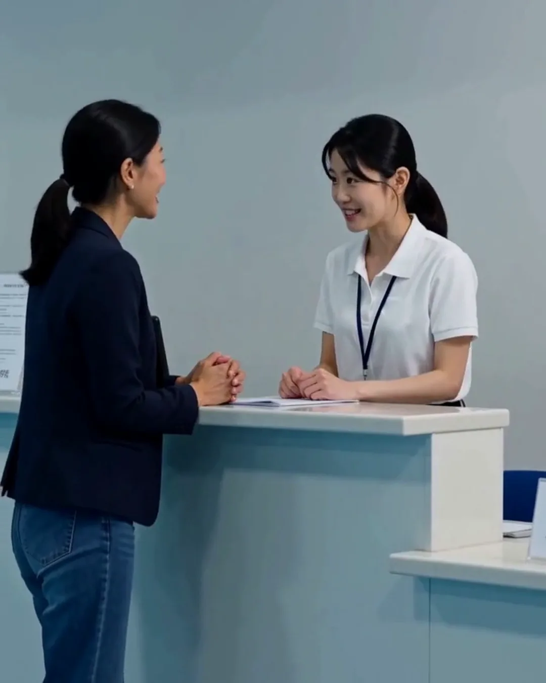 市民プールの受付で、係の女性と外国人の女性利用者がカウンターを挟んで話している
