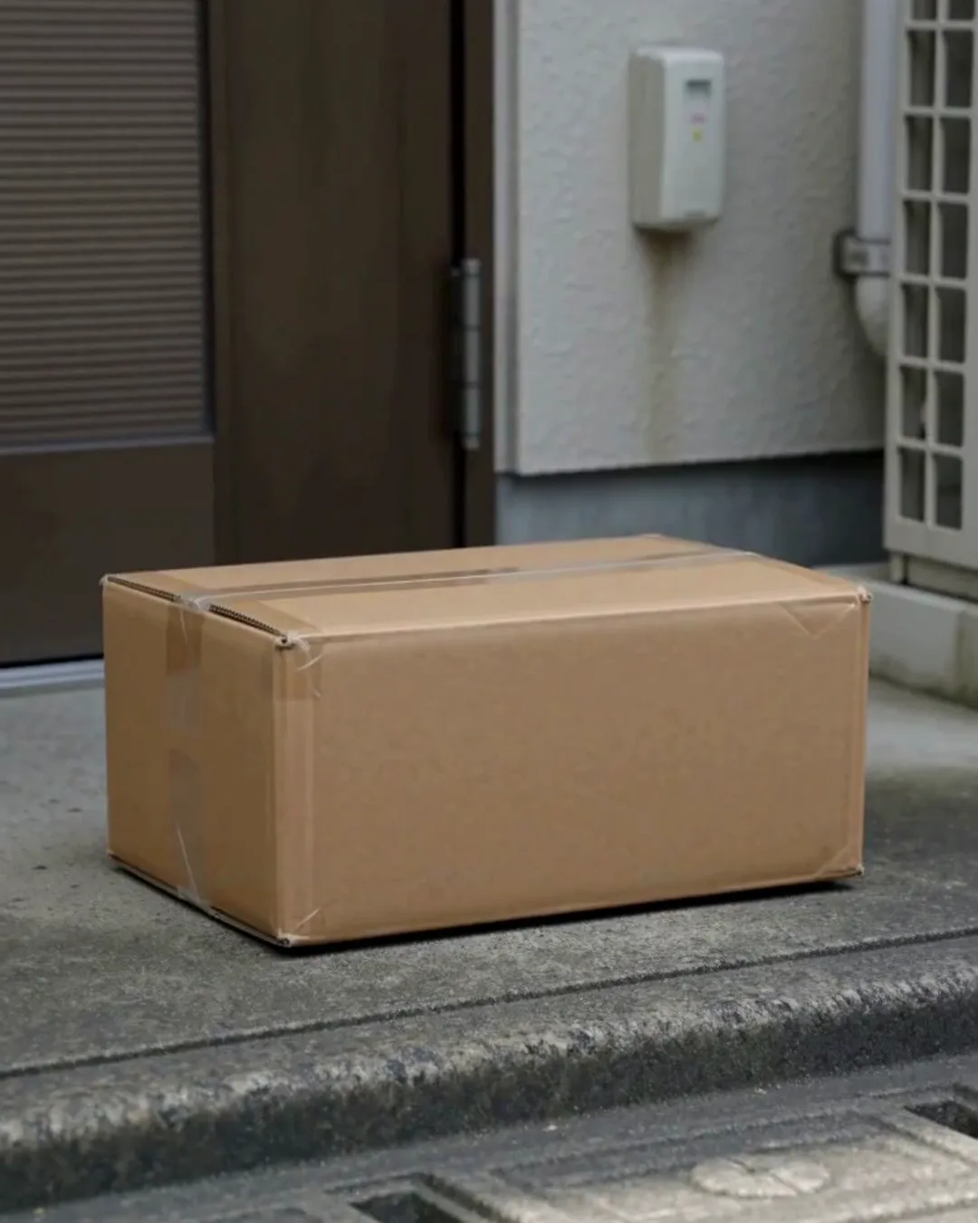 鉄の扉の前のコンクリートの床に置かれた、無地の段ボール箱