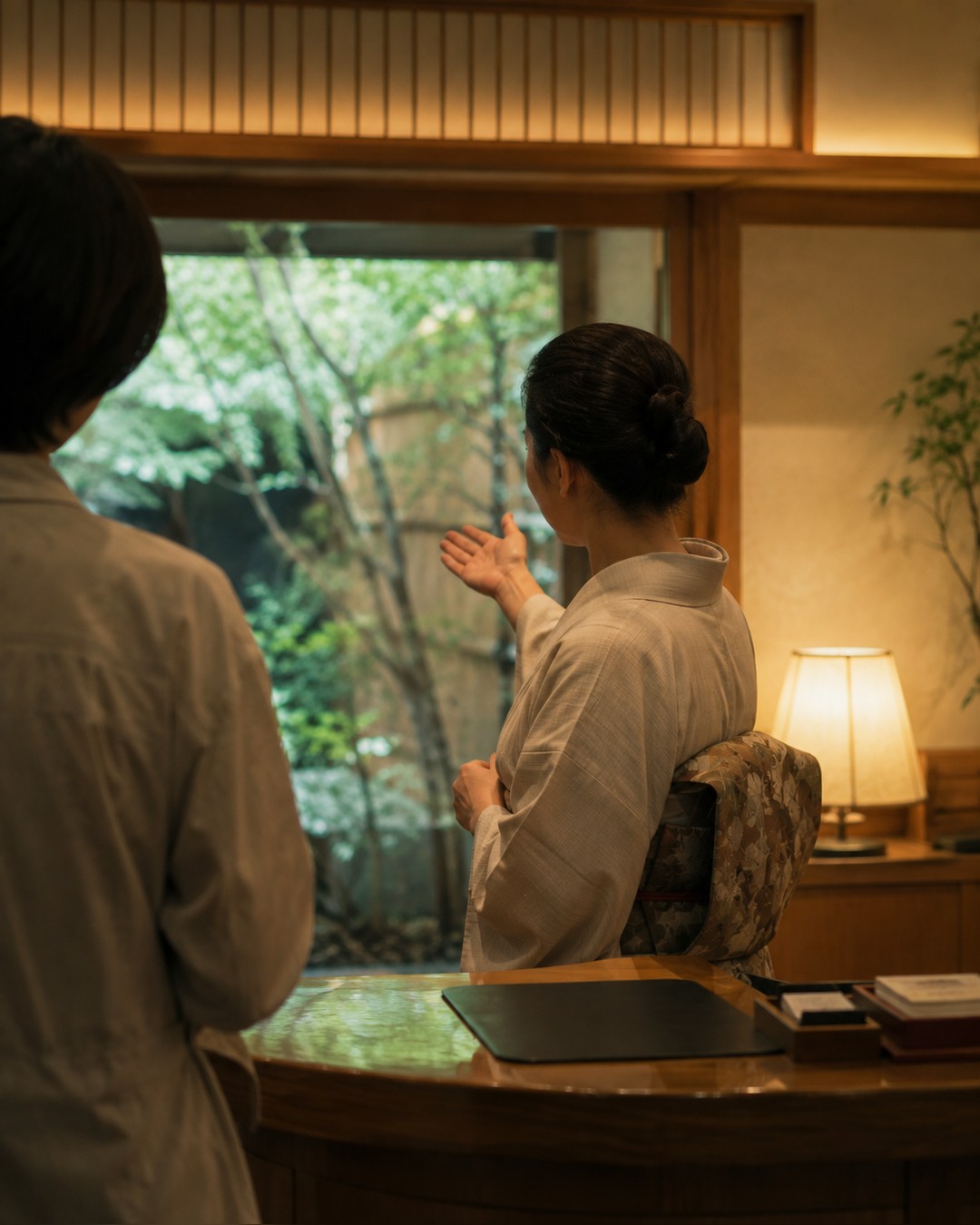 夜の旅館の玄関。女将が外国人の宿泊客に案内をしている