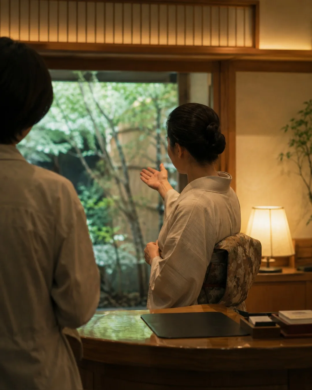 夜の旅館の玄関。女将が外国人の宿泊客に案内をしている