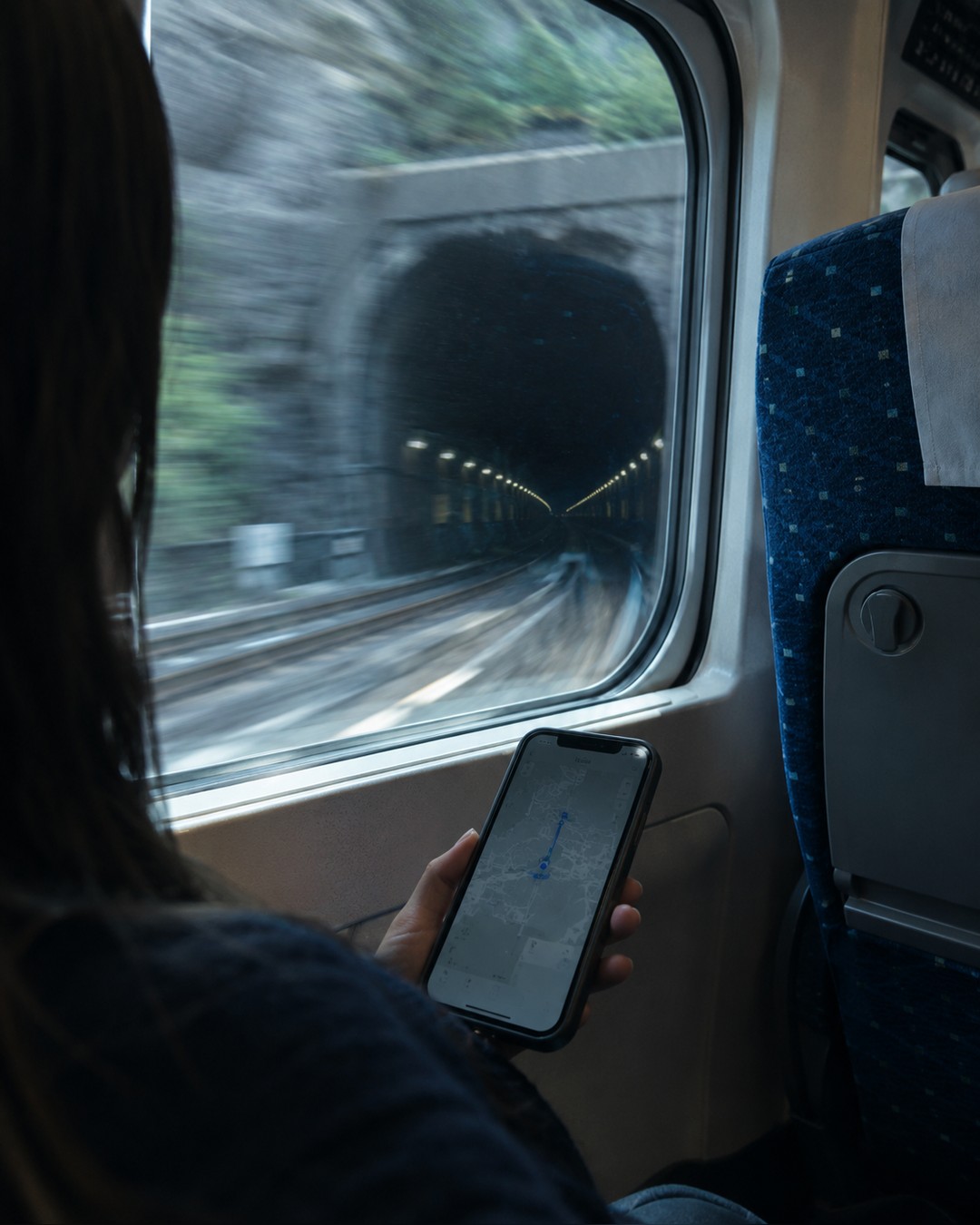新幹線の車内。窓の外を見ながらスマートフォンを持っている手元
