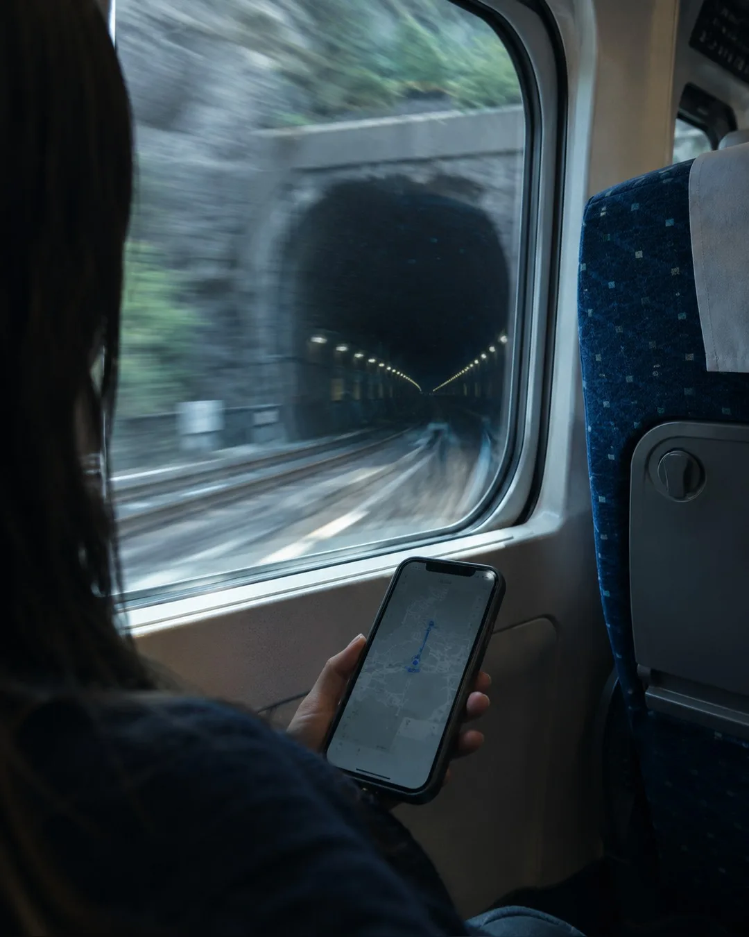 新幹線の車内。窓の外を見ながらスマートフォンを持っている手元